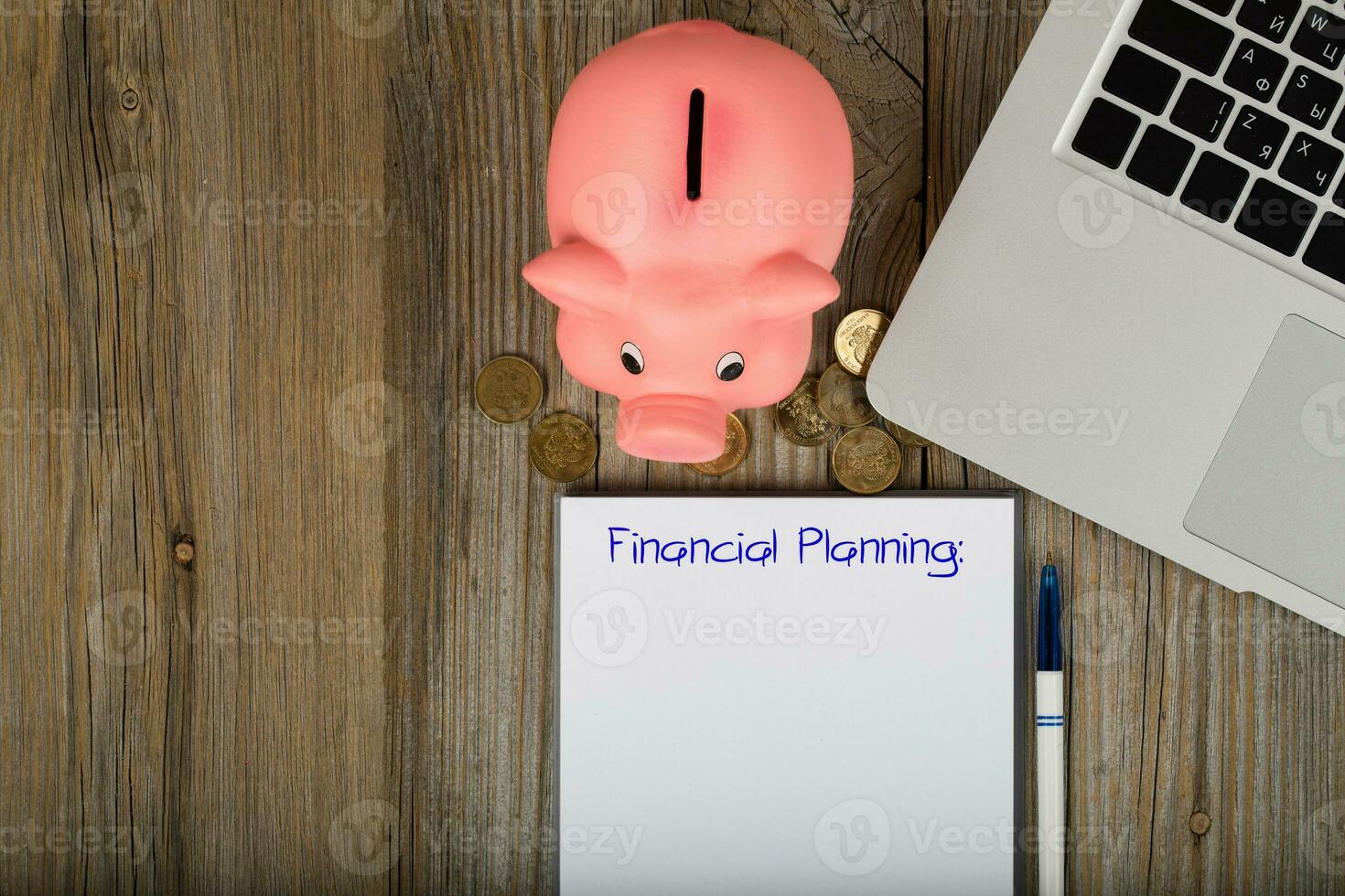 Financial planning is written on a sheet of paper. Pink piggy bank close to the laptop. photo