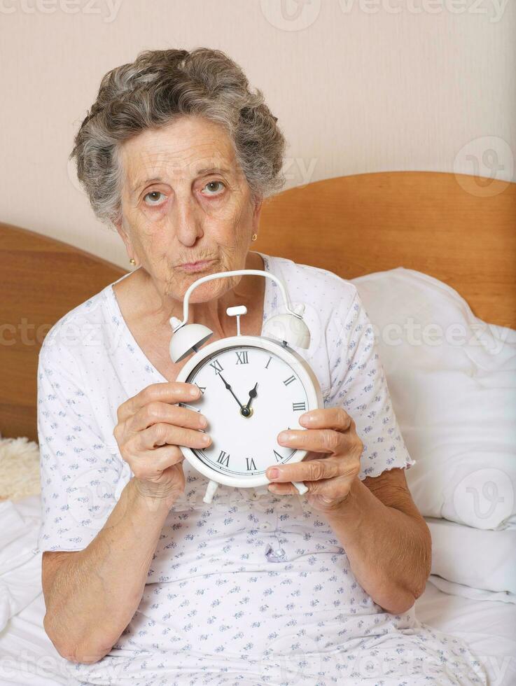 Old woman with vintage alarm clock photo