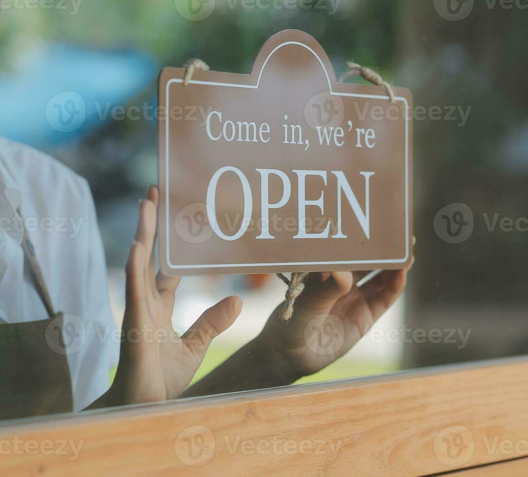 Open. barista, waitress woman wearing protection face mask turning open sign board on glass door in modern cafe coffee shop, cafe restaurant, retail store, small business owner, food and drink concept photo