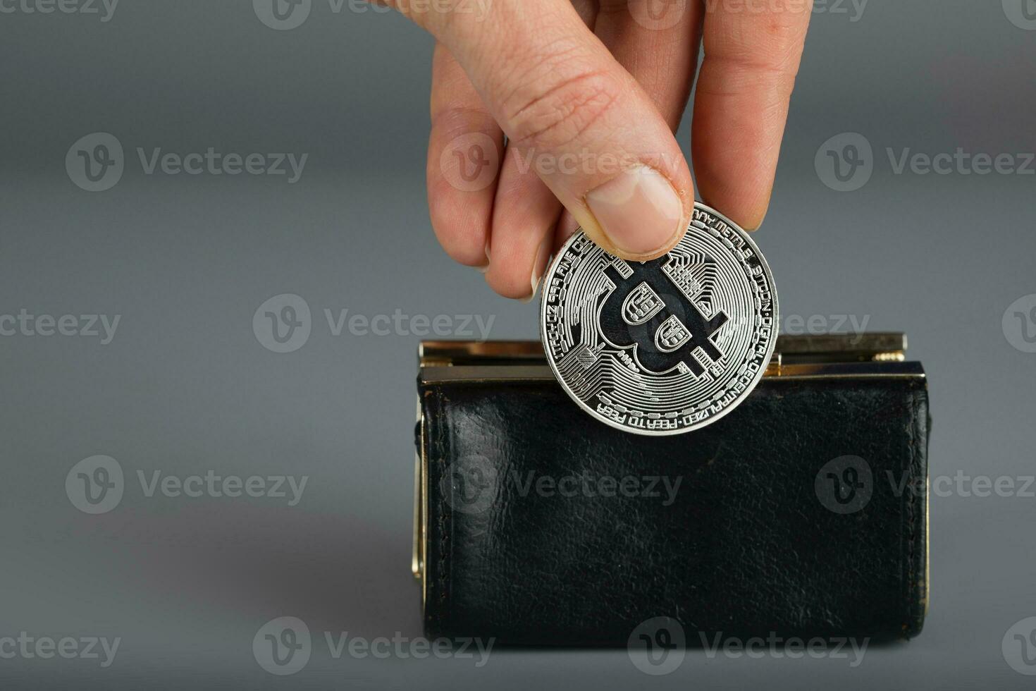 Person puts bitcoin in a black wallet. photo