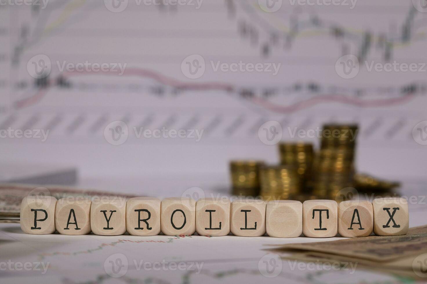 Words PAYROLL TAX composed of wooden letter. Stacks of coins in the background. photo