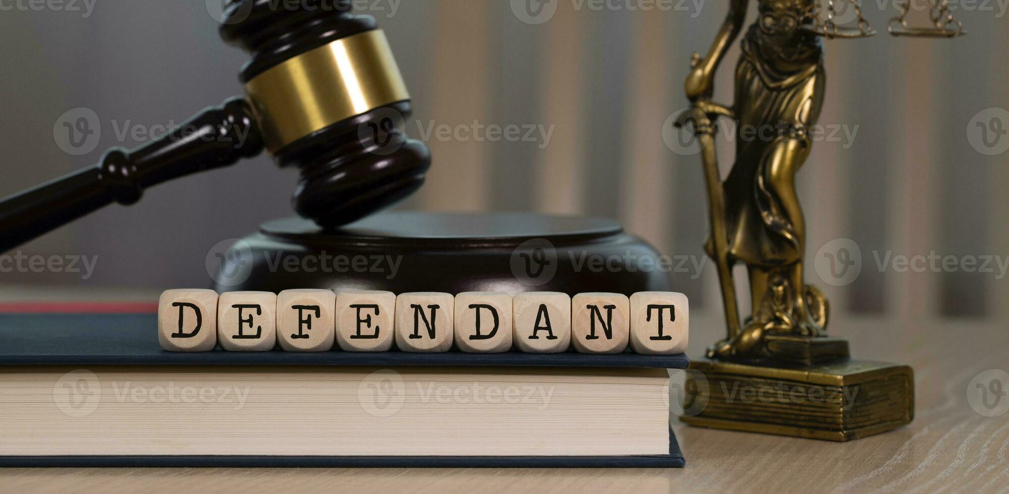 Word DEFENDANT composed of wooden dices. Wooden gavel and statue of Themis in the background. photo