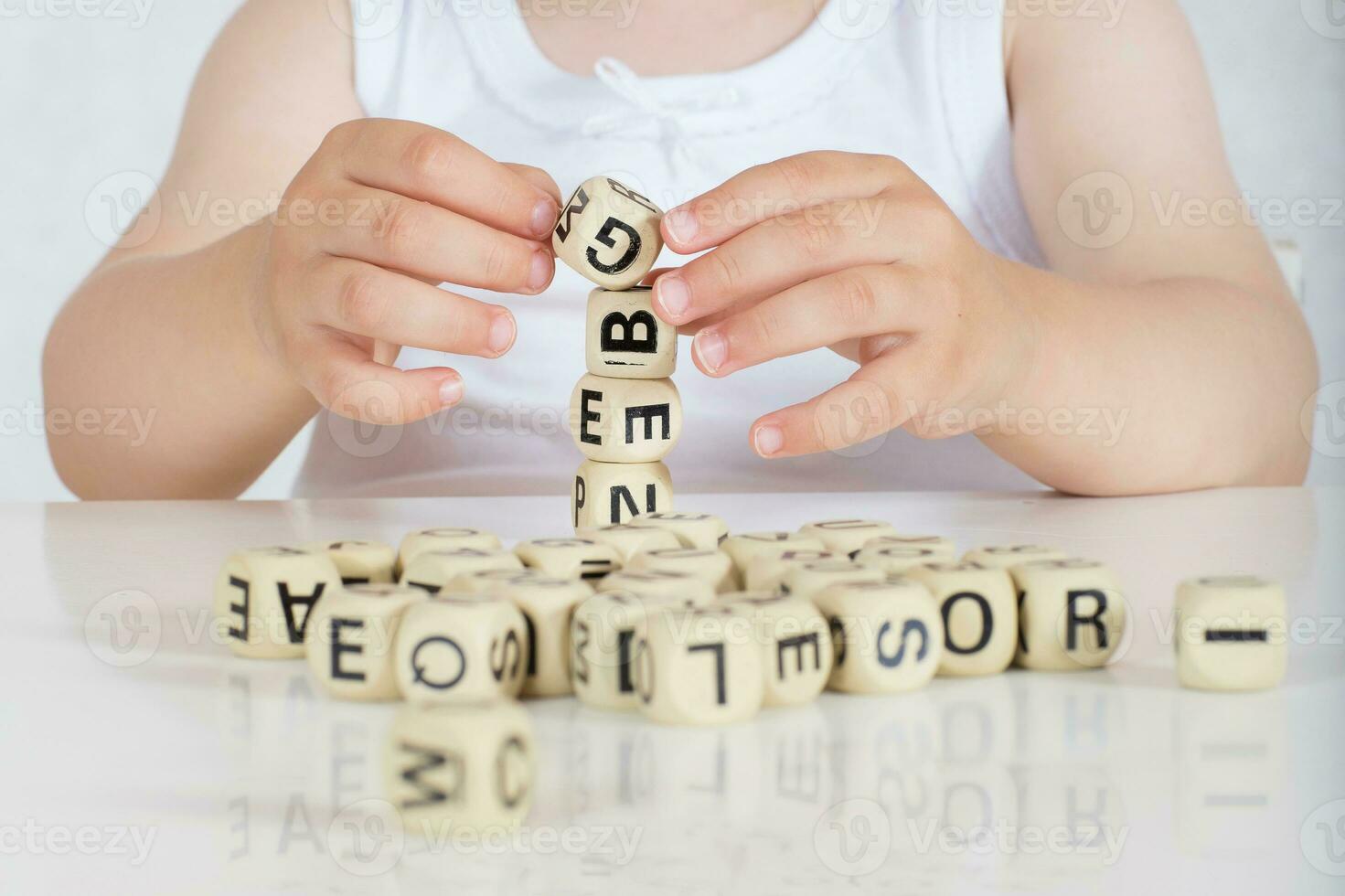 Small girl composes words from letters. Closeup photo