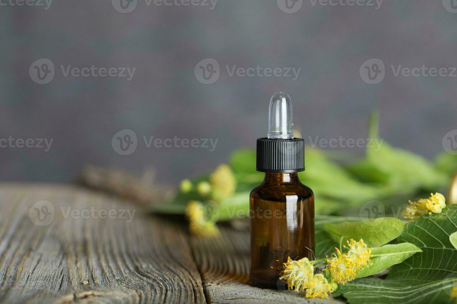 Linden blossoms absolute oil in a glass bottle on a wooden surface. photo