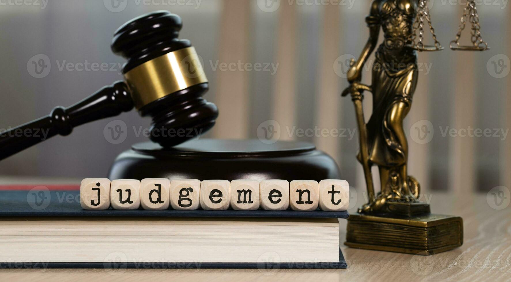 Word  JUDGEMENT composed of wooden dices. Wooden gavel and statue of Themis in the background. photo