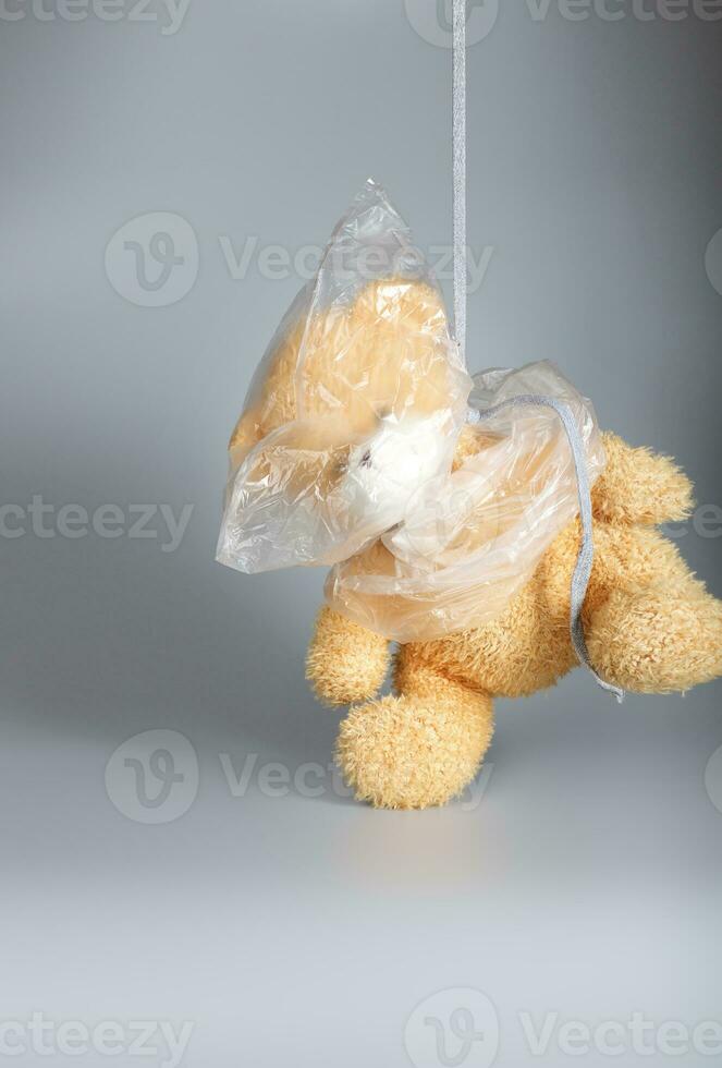 Head of a plush teddy bear is covered by plastic bag. photo