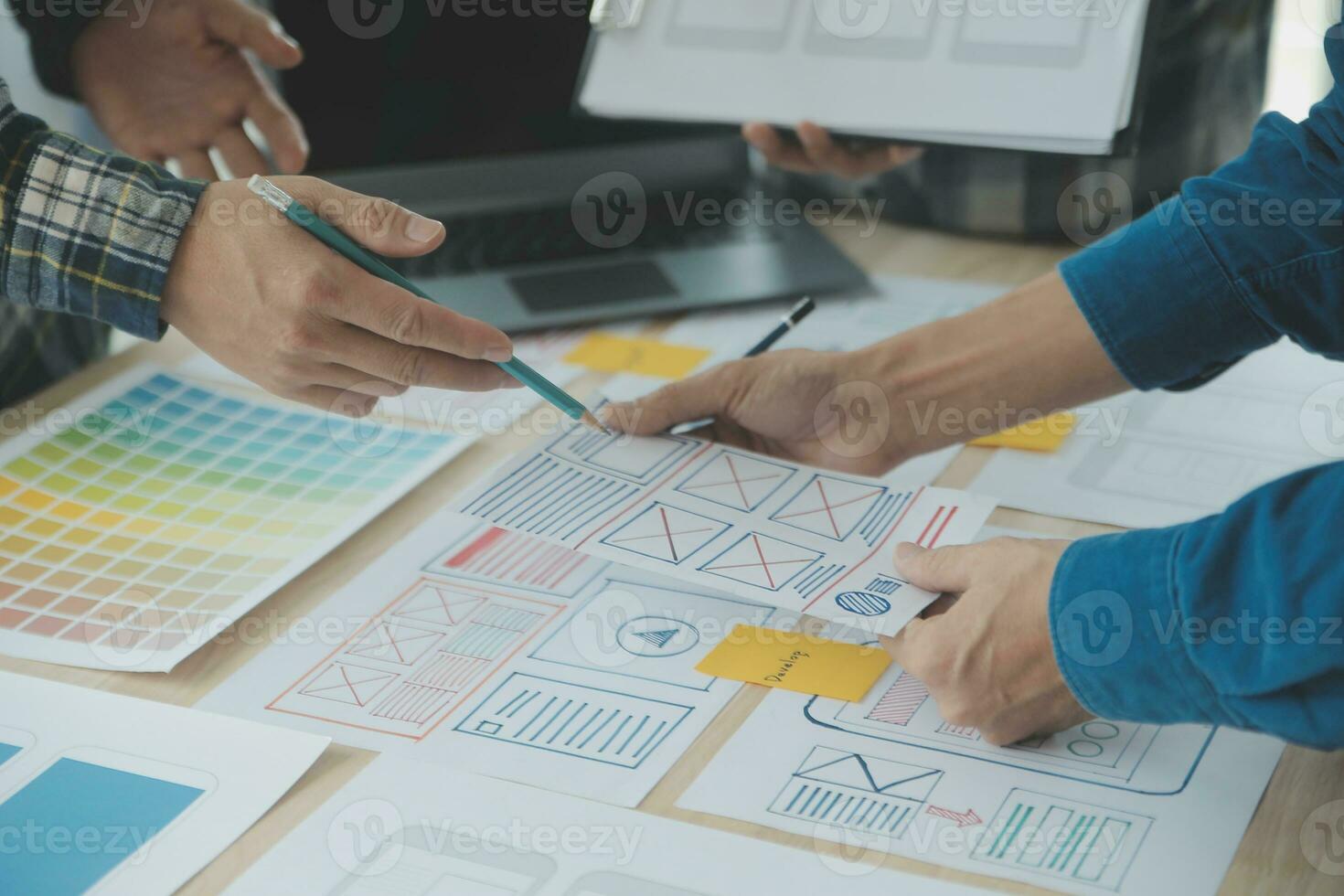 Close up ux developer and ui designer brainstorming about mobile app interface wireframe design on table with customer breif and color code at modern office.Creative digital development agency photo
