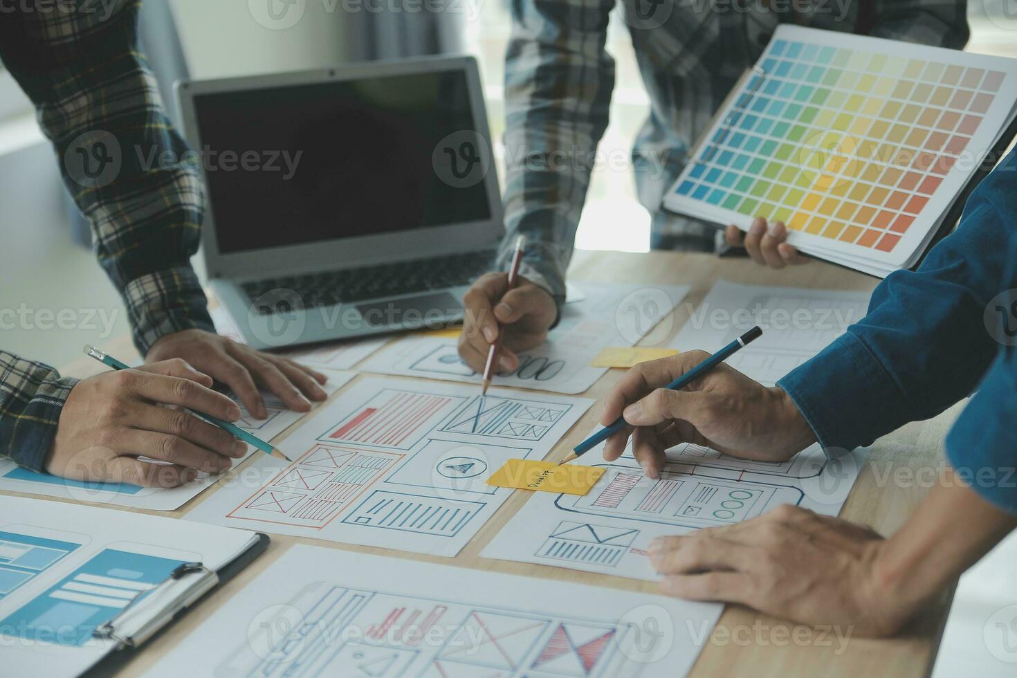 Close up ux developer and ui designer brainstorming about mobile app interface wireframe design on table with customer breif and color code at modern office.Creative digital development agency photo