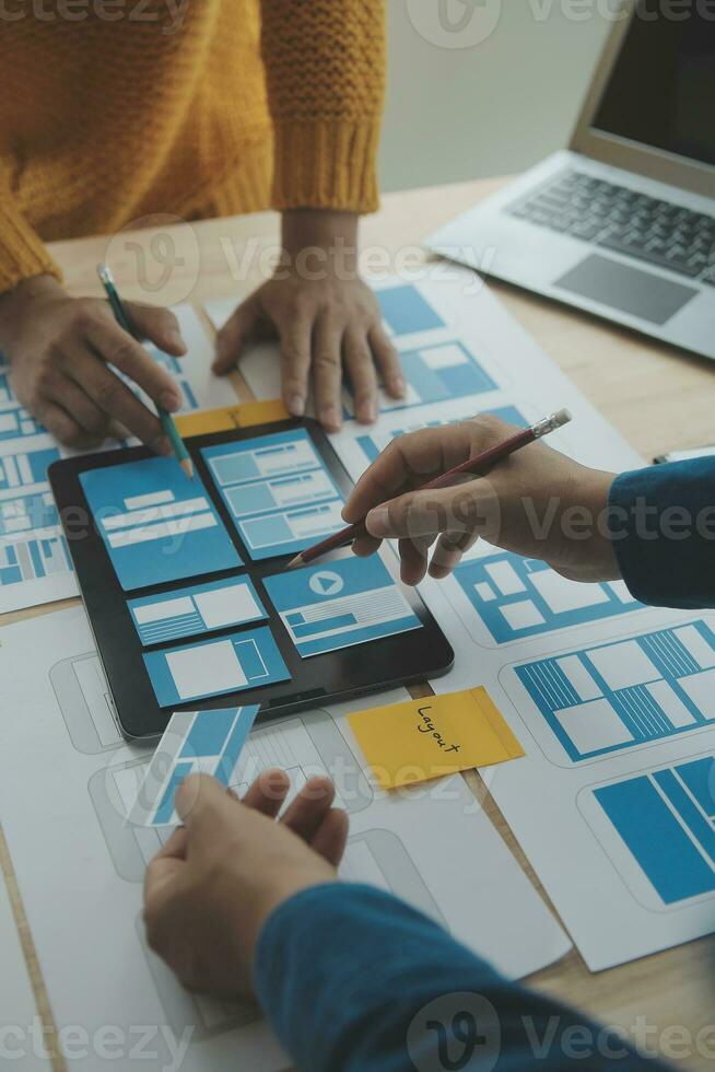 Close up ux developer and ui designer brainstorming about mobile app interface wireframe design on table with customer breif and color code at modern office.Creative digital development agency photo