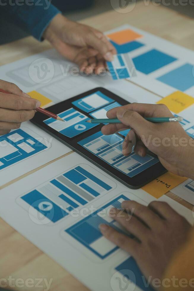 Close up ux developer and ui designer brainstorming about mobile app interface wireframe design on table with customer breif and color code at modern office.Creative digital development agency photo