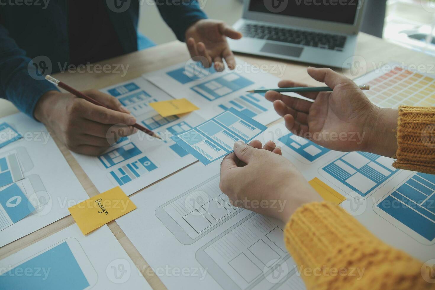 Close up ux developer and ui designer brainstorming about mobile app interface wireframe design on table with customer breif and color code at modern office.Creative digital development agency photo