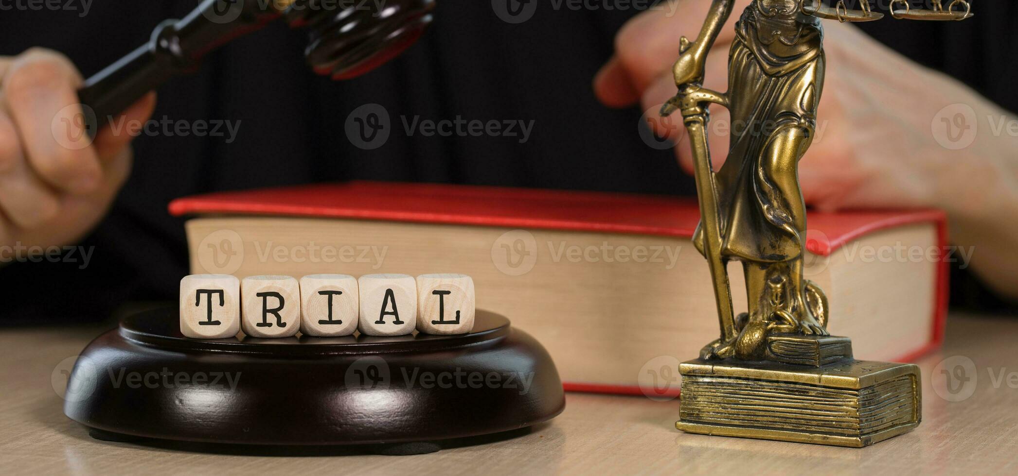 Word TRIAL composed of wooden dices. Wooden gavel and statue of Themis in the background. photo