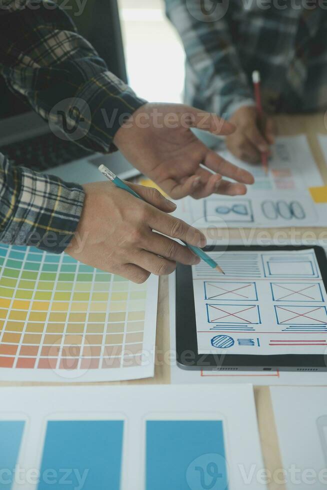 Close up ux developer and ui designer brainstorming about mobile app interface wireframe design on table with customer breif and color code at modern office.Creative digital development agency photo
