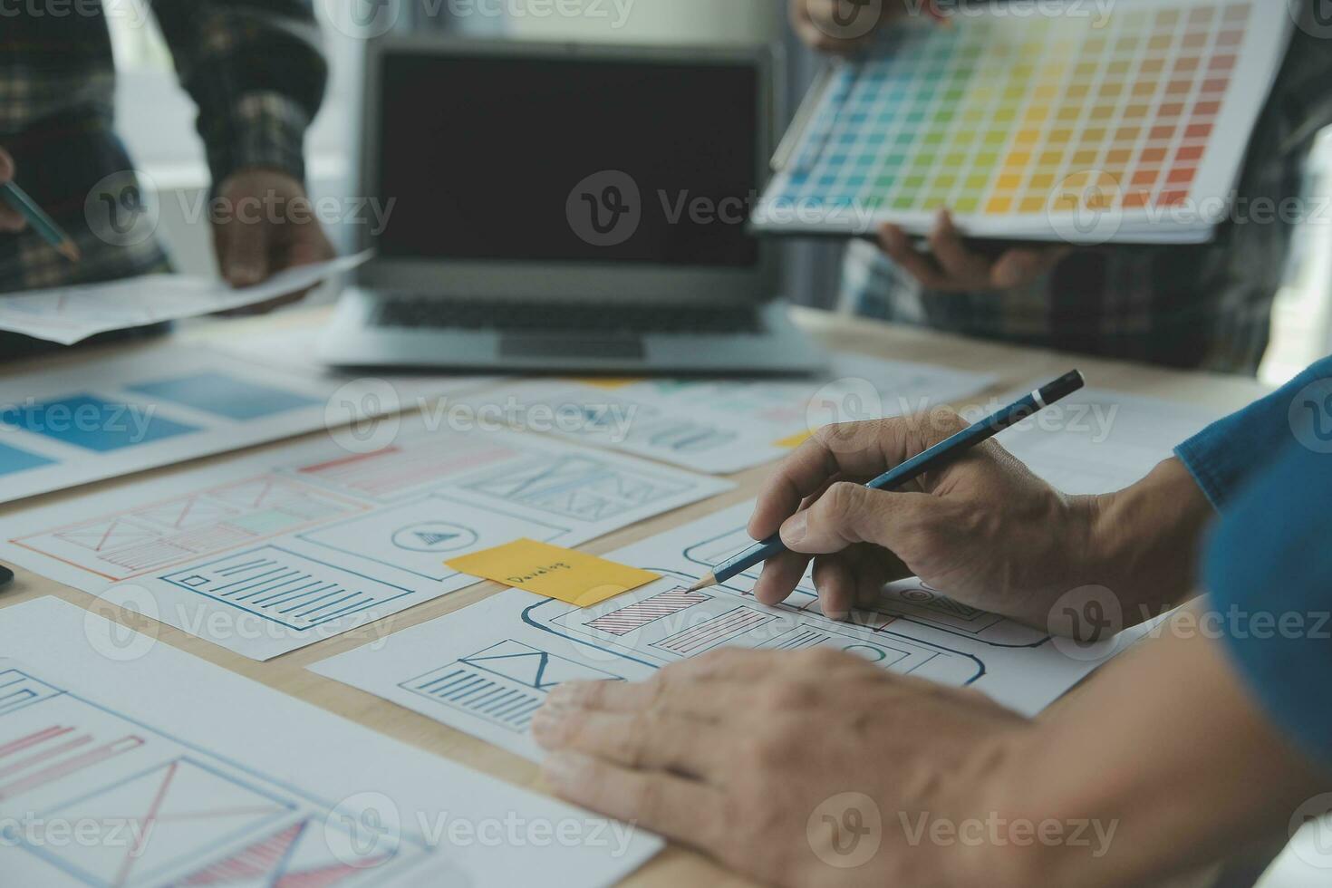 Close up ux developer and ui designer brainstorming about mobile app interface wireframe design on table with customer breif and color code at modern office.Creative digital development agency photo