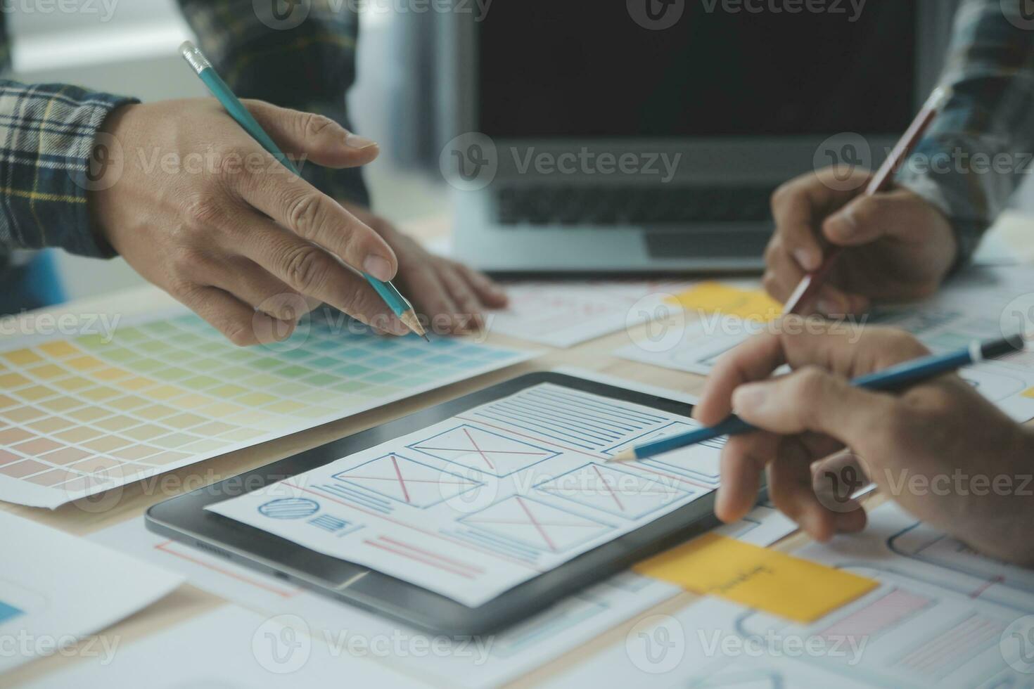 Close up ux developer and ui designer brainstorming about mobile app interface wireframe design on table with customer breif and color code at modern office.Creative digital development agency photo