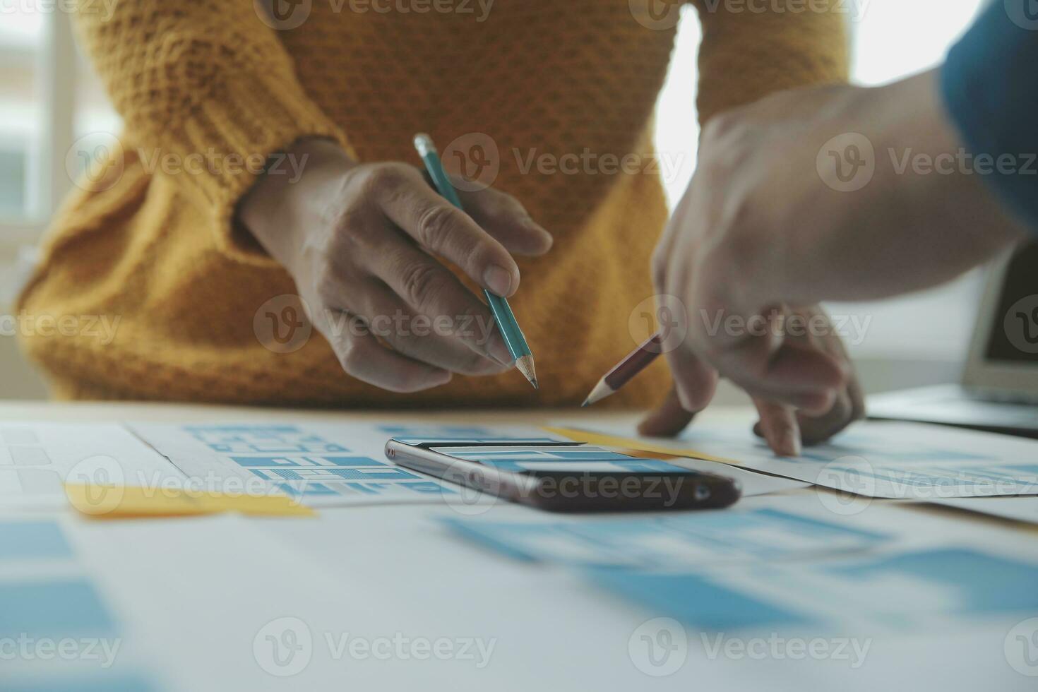 Close up ux developer and ui designer brainstorming about mobile app interface wireframe design on table with customer breif and color code at modern office.Creative digital development agency photo