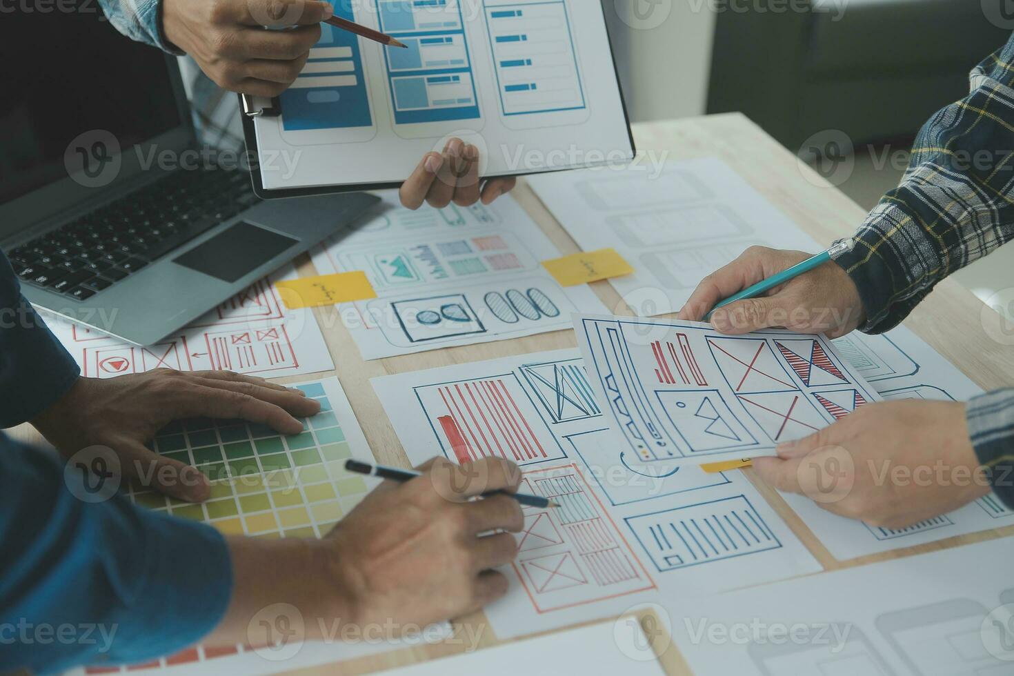 Close up ux developer and ui designer brainstorming about mobile app interface wireframe design on table with customer breif and color code at modern office.Creative digital development agency photo