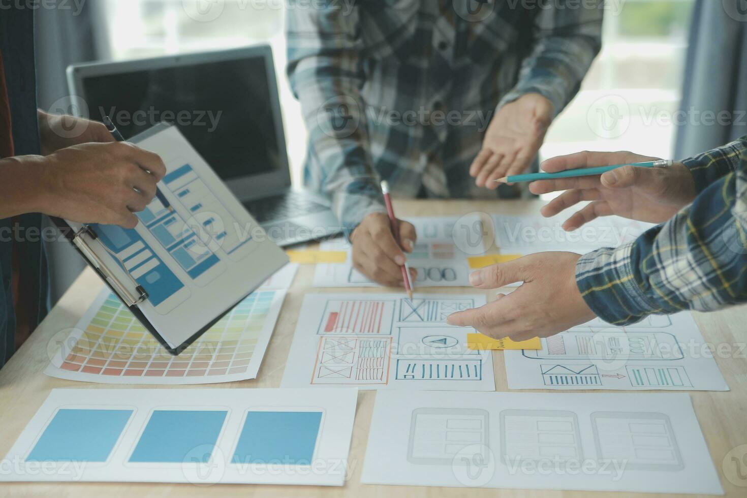 Close up ux developer and ui designer brainstorming about mobile app interface wireframe design on table with customer breif and color code at modern office.Creative digital development agency photo