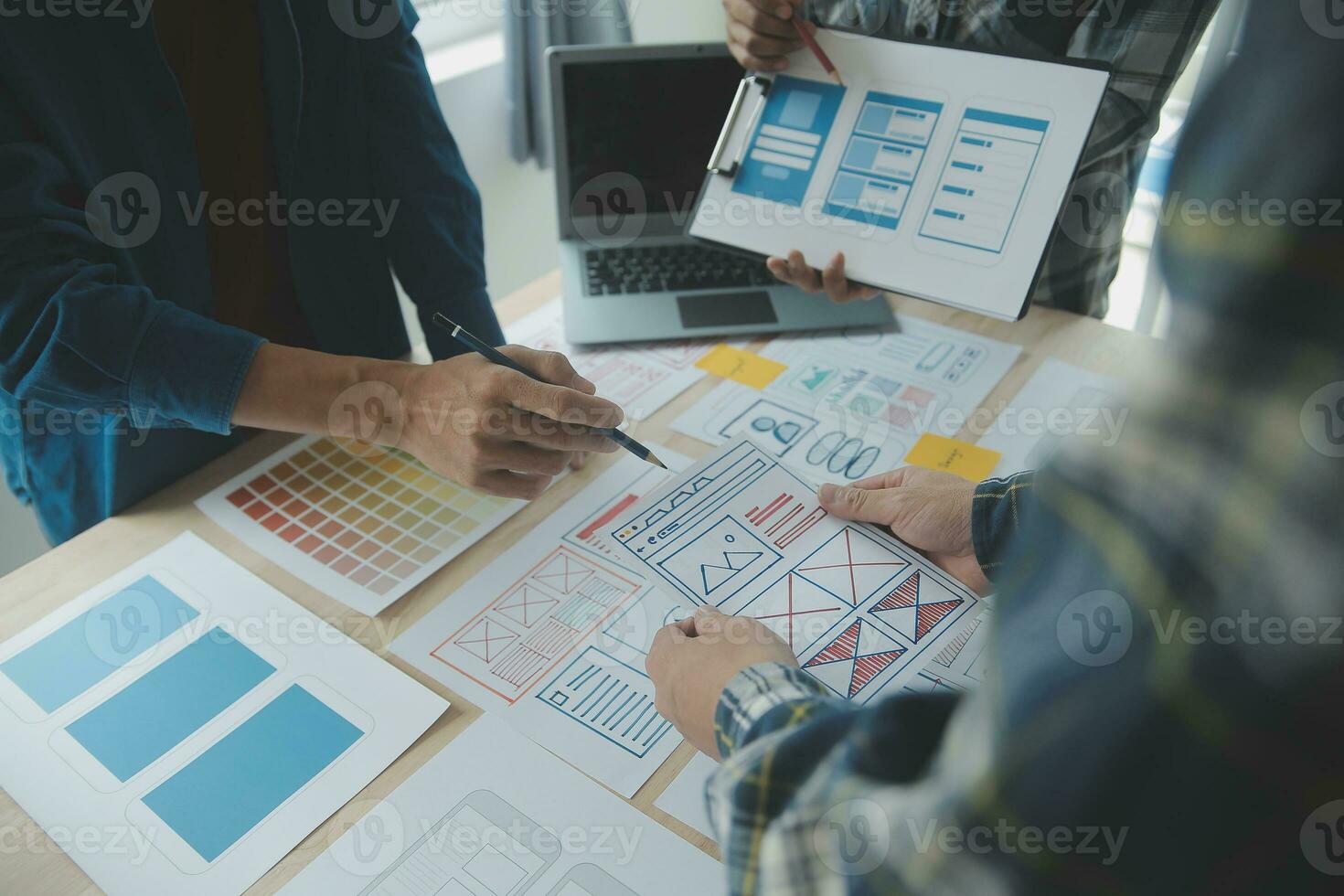 Close up ux developer and ui designer brainstorming about mobile app interface wireframe design on table with customer breif and color code at modern office.Creative digital development agency photo