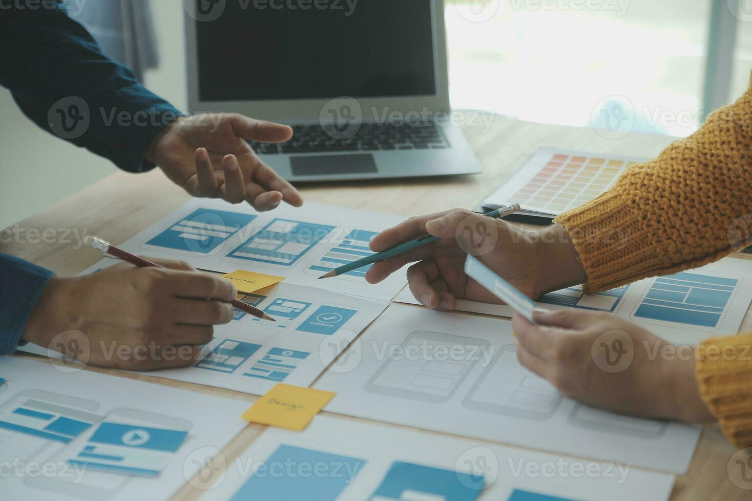 Close up ux developer and ui designer brainstorming about mobile app interface wireframe design on table with customer breif and color code at modern office.Creative digital development agency photo