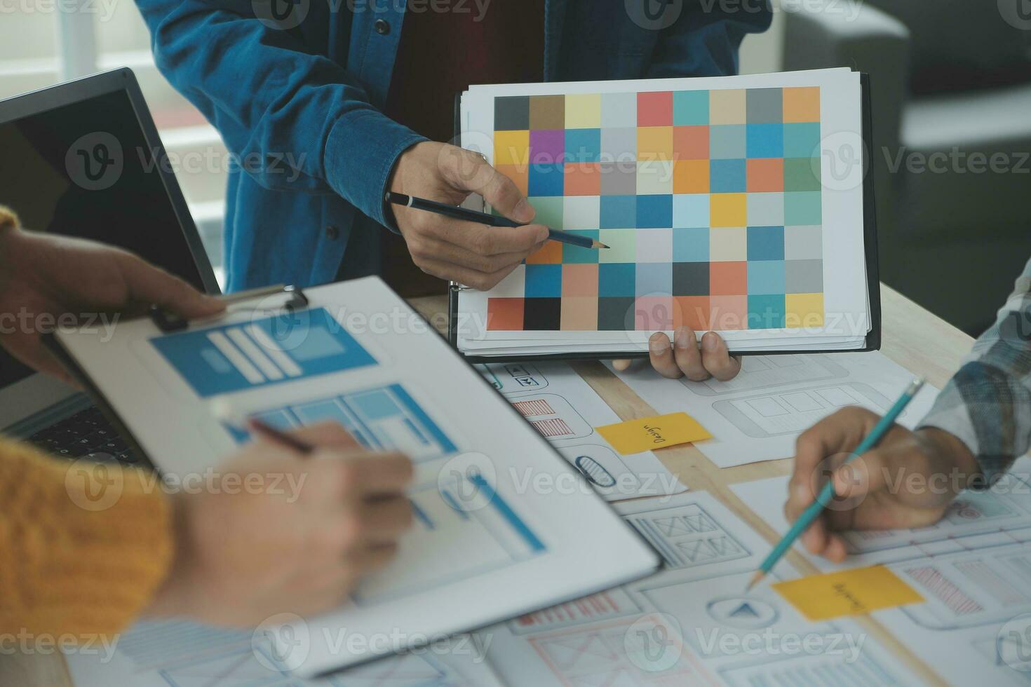 Close up ux developer and ui designer brainstorming about mobile app interface wireframe design on table with customer breif and color code at modern office.Creative digital development agency photo