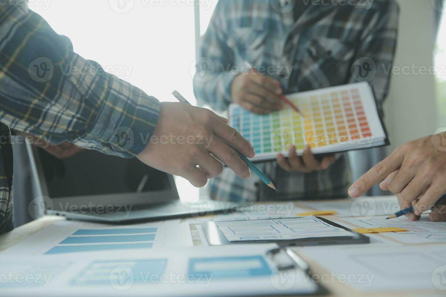 Close up ux developer and ui designer brainstorming about mobile app interface wireframe design on table with customer breif and color code at modern office.Creative digital development agency photo