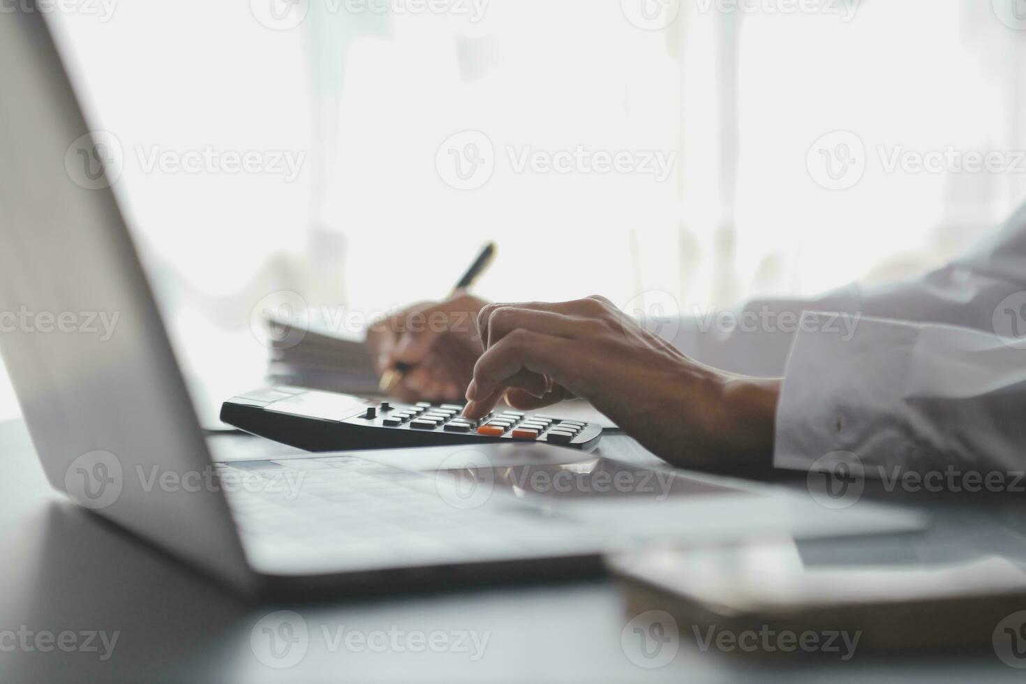 Asian Business woman using calculator and laptop for doing math finance on an office desk, tax, report, accounting, statistics, and analytical research concept photo