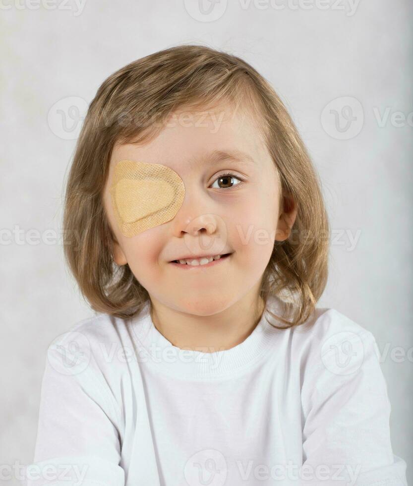 Boy with one eye covered by eye pad and with eye glasses. photo