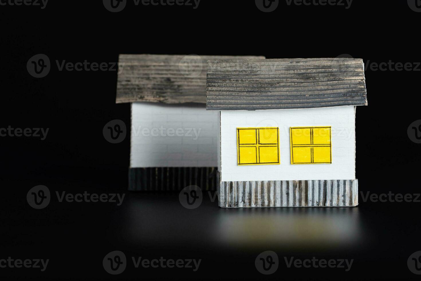 Two small paper houses on a black surface. photo