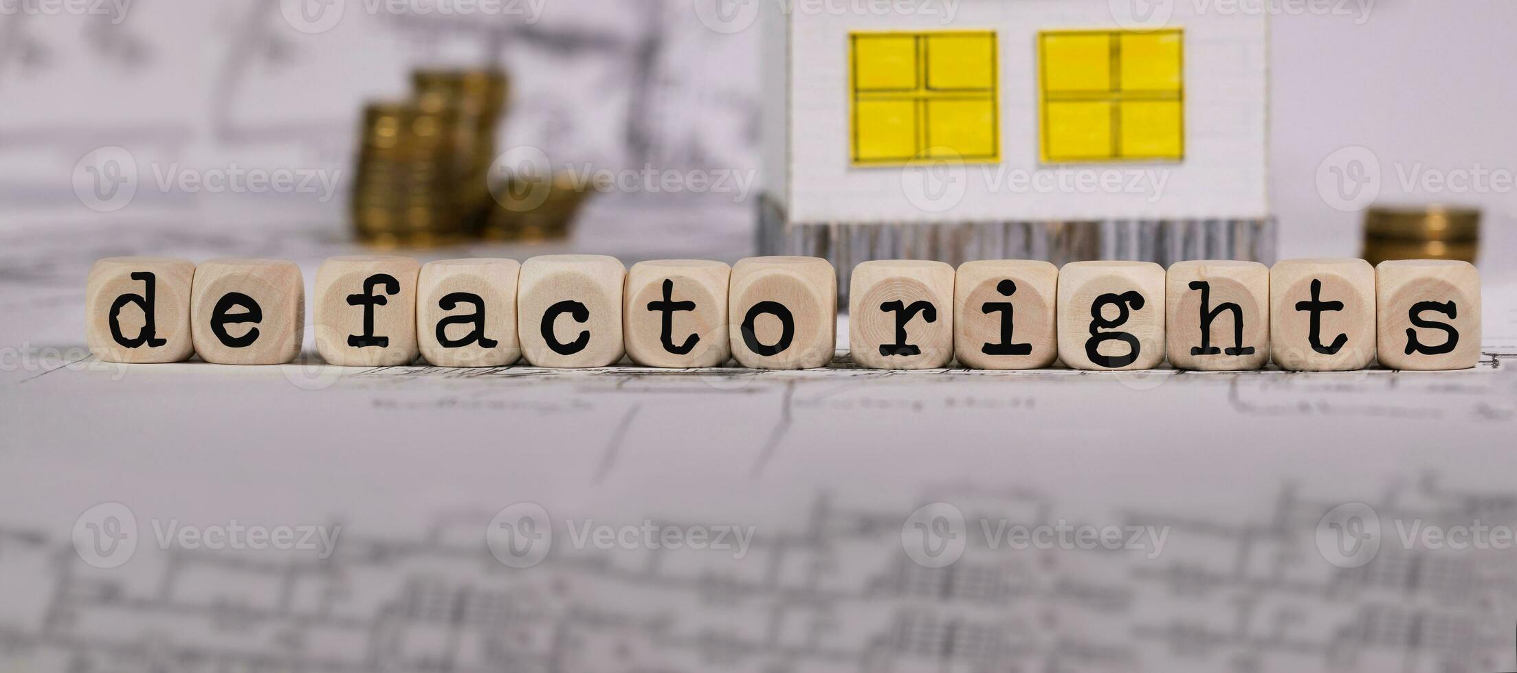 Words DE FACTO RIGHTS composed of wooden letters. Small paper house in the background. photo