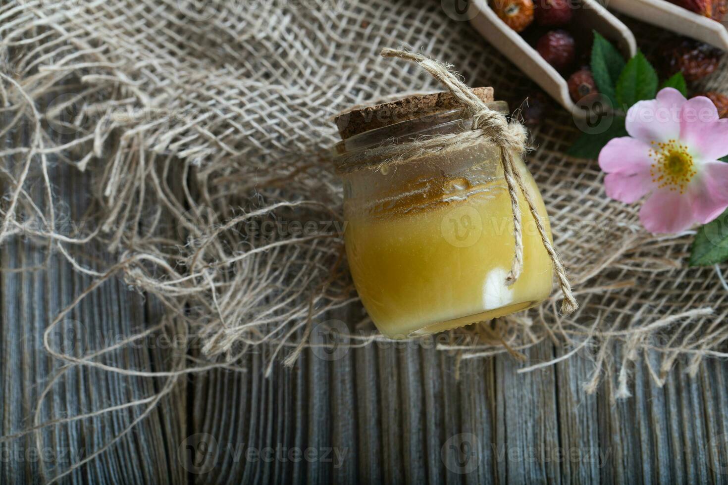 Wild rose hip honey in a glass bottle on a wooden surface. photo