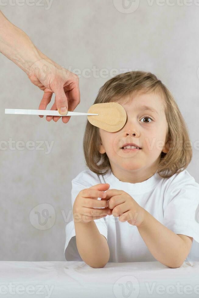 Ophthalmologist closes boy's eyes with eye pad. photo