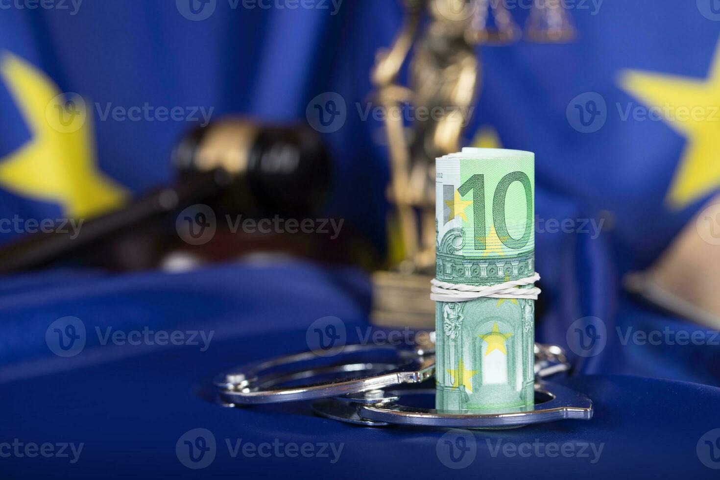 Pile of 100 euros surrounded by handcuffs on a flag of EU. photo