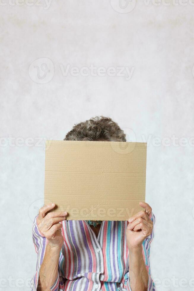 Old woman with a piece of carton paper photo