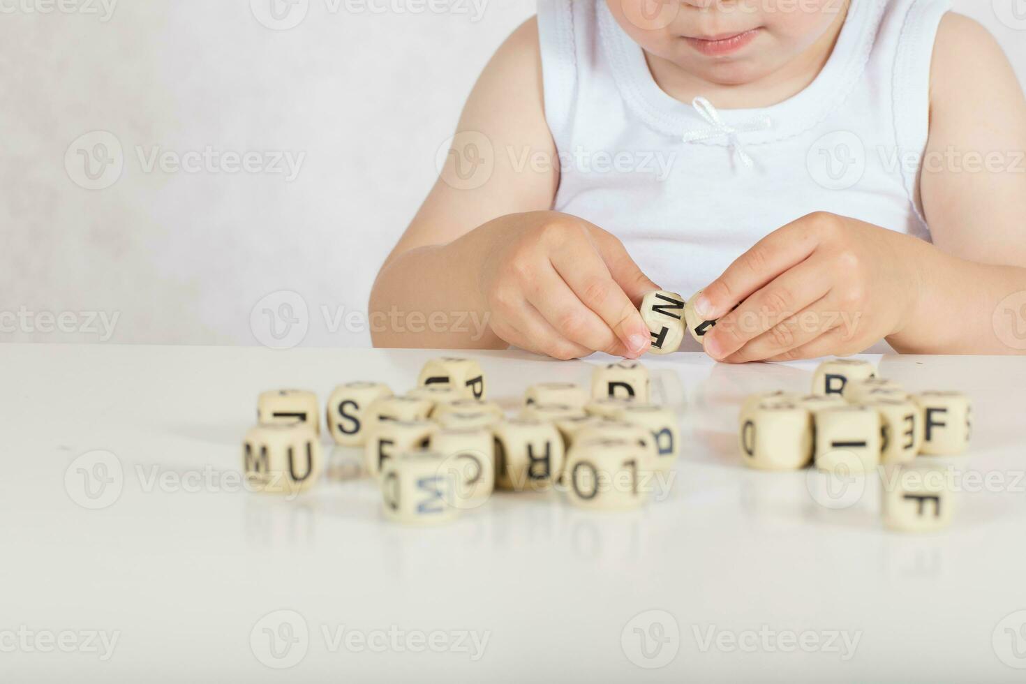 Small girl composes words from letters. Closeup photo