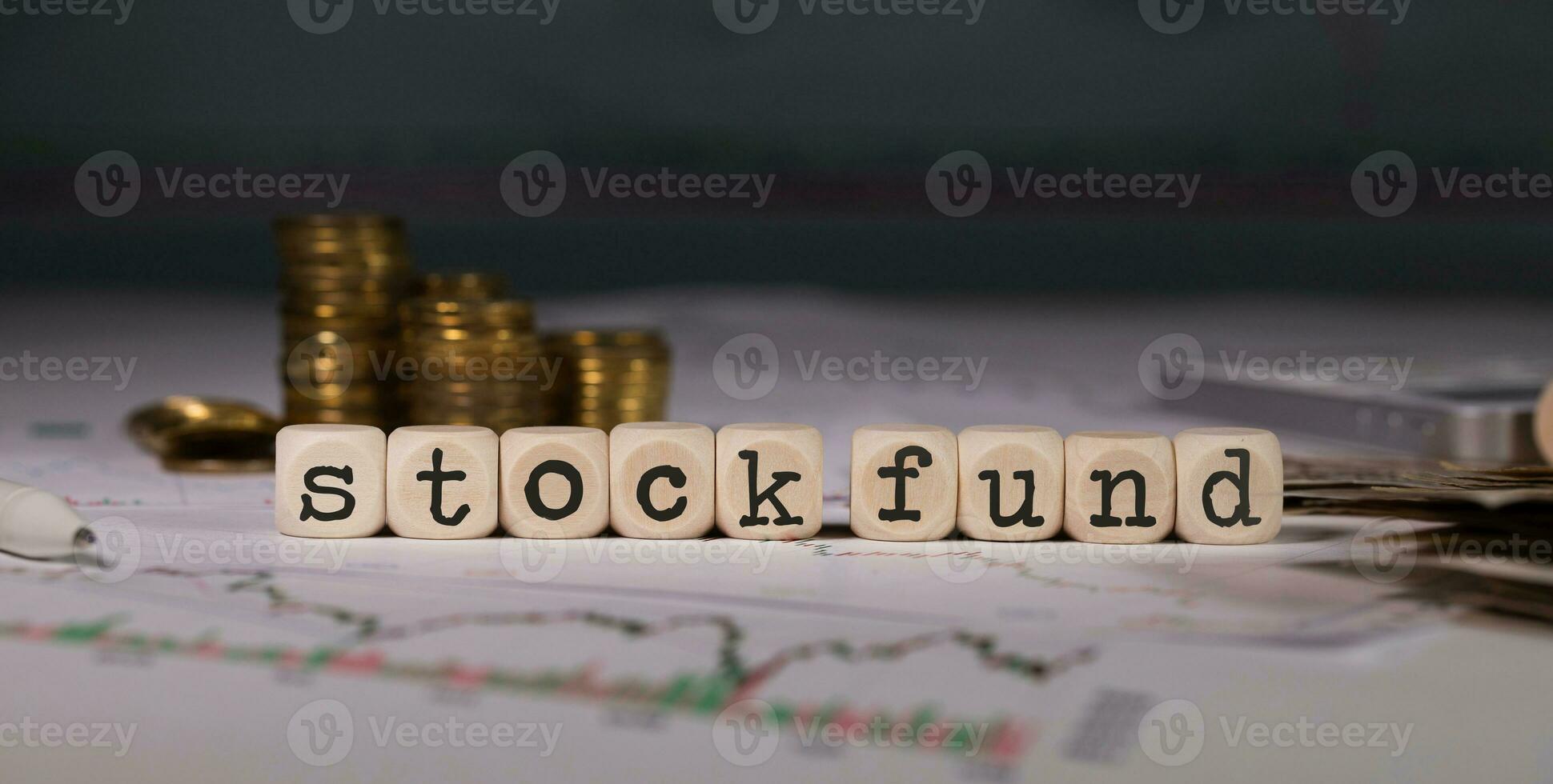 Words STOCK FUND composed of wooden letter. Stacks of coins in the background. photo