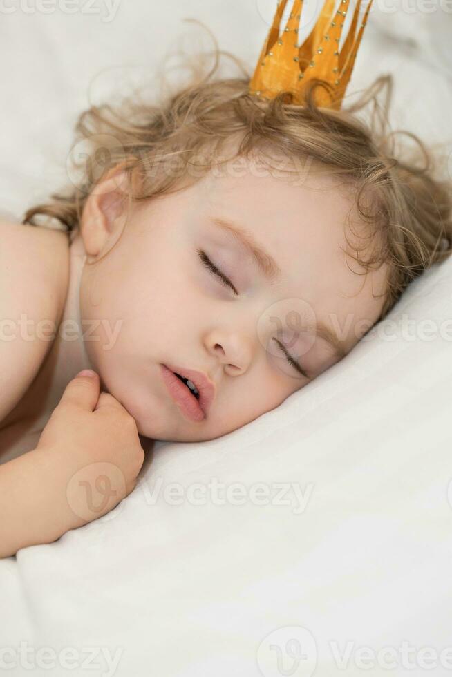 Small girl is sleeping in her white bed. Closeup photo