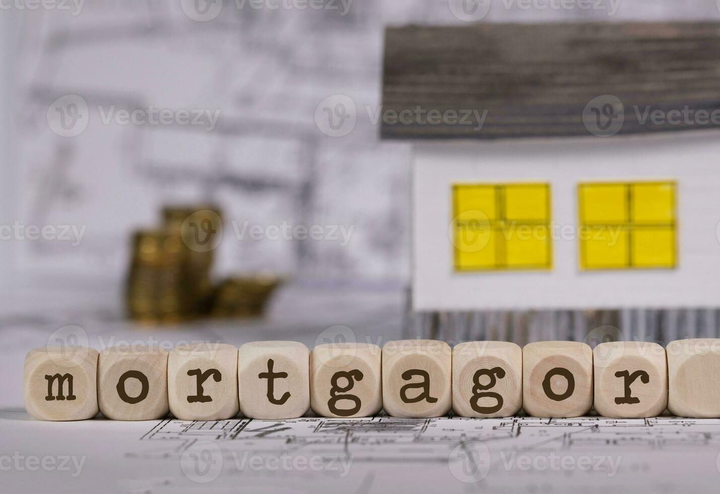 Word MORTGAGOR composed of wooden letter. Small paper house in the background. photo