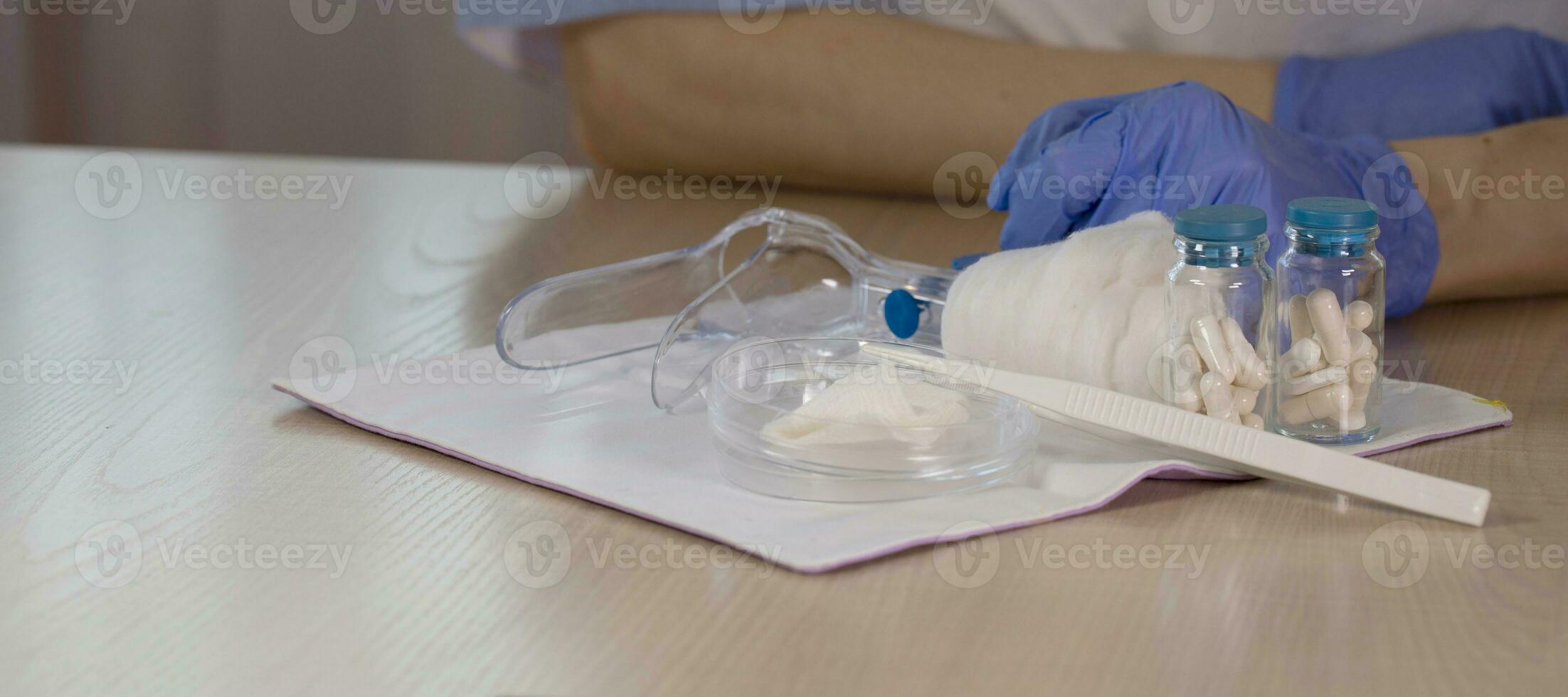 Glass bottles with pills in front of gynecologist Vaginal speculum in the background. photo