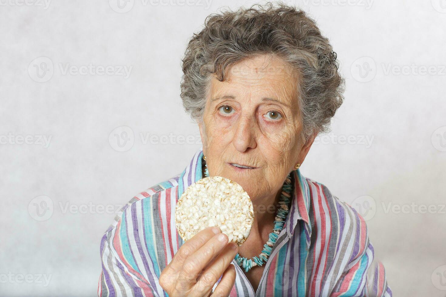 Old woman is eating dried bread photo