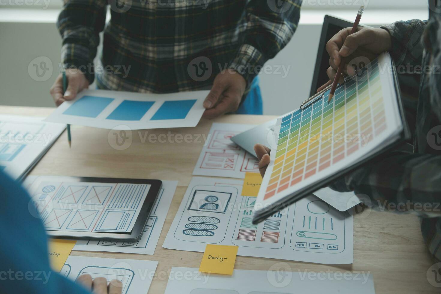Close up ux developer and ui designer brainstorming about mobile app interface wireframe design on table with customer breif and color code at modern office.Creative digital development agency photo