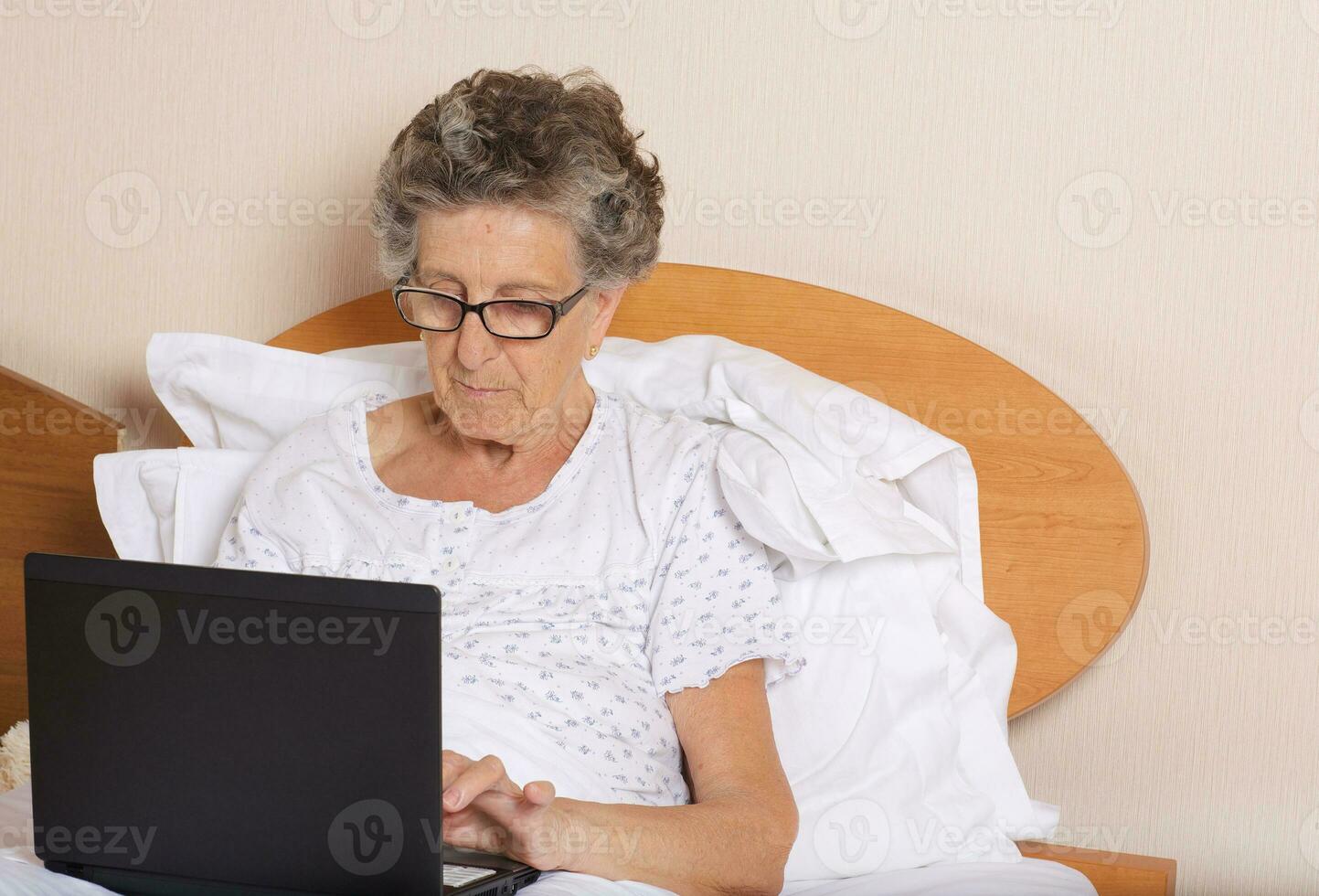 Old woman is communicating through her computer wit hrelatives photo