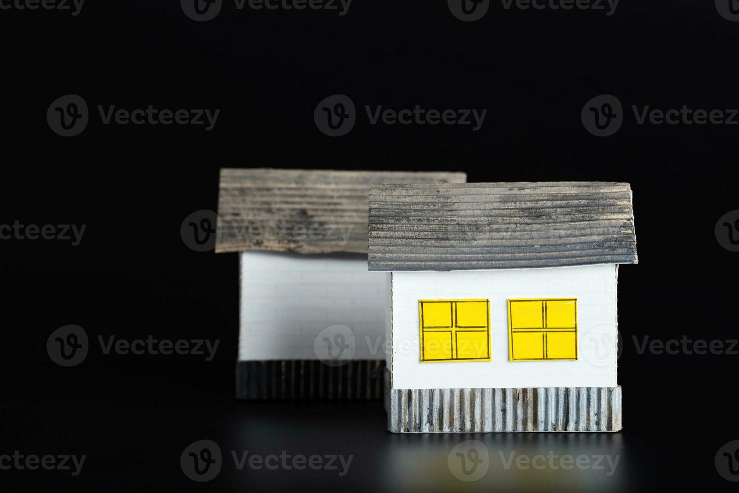 Two small paper houses on a black surface. photo