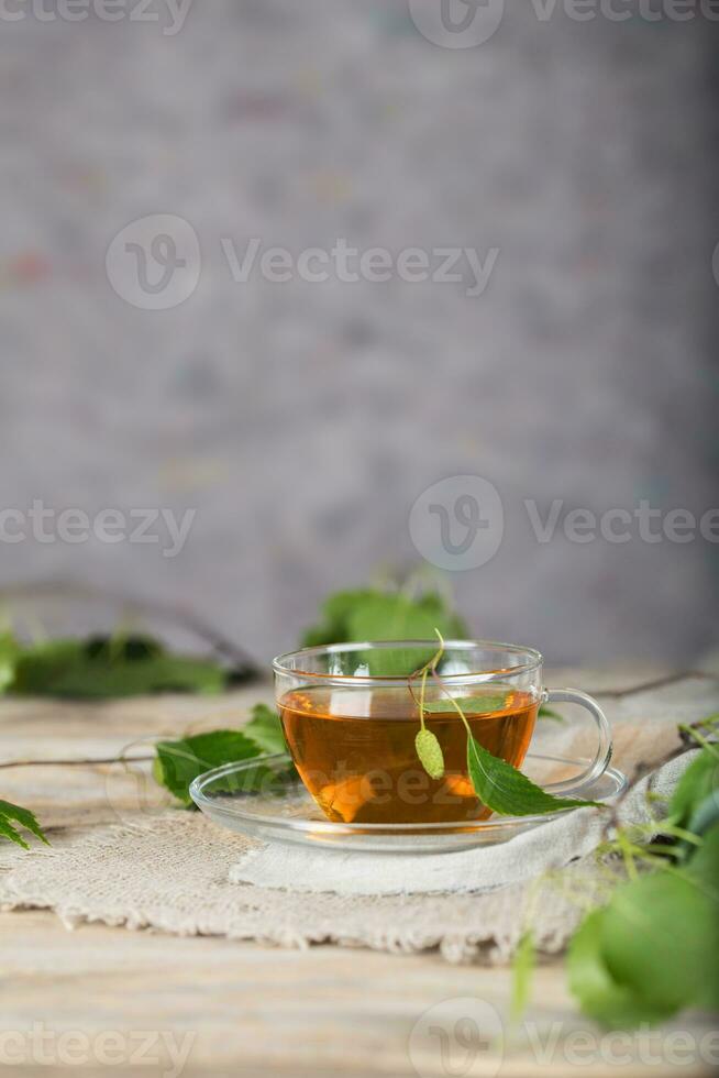 Birch leaf train a glass cup on a wooden surface. photo