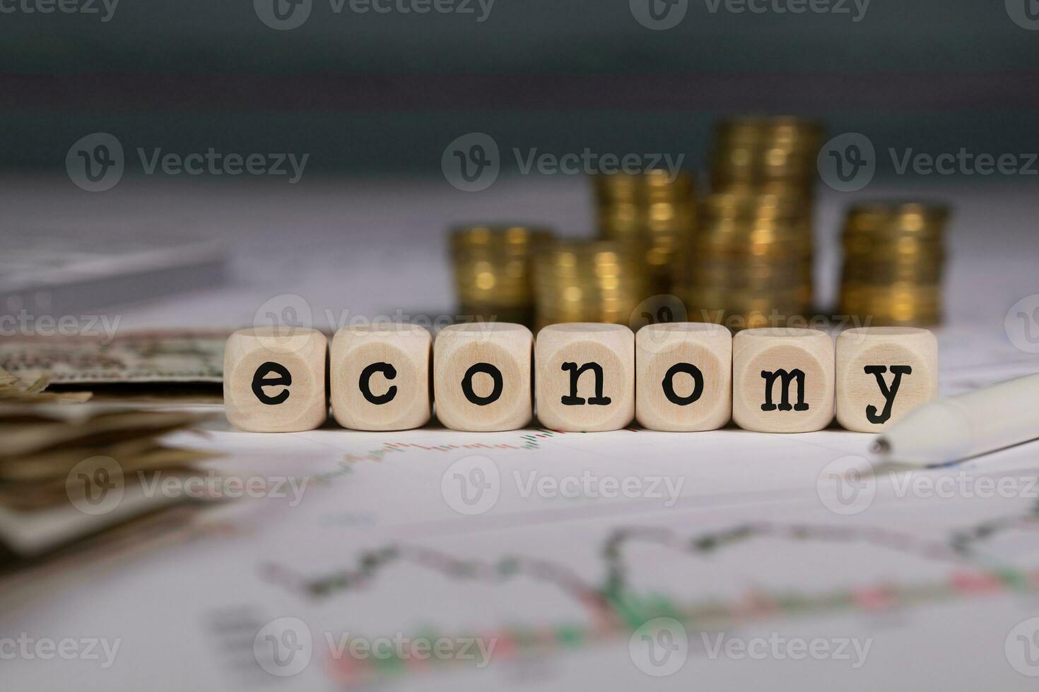 palabra economía compuesto de de madera carta. pilas de monedas en el antecedentes. foto