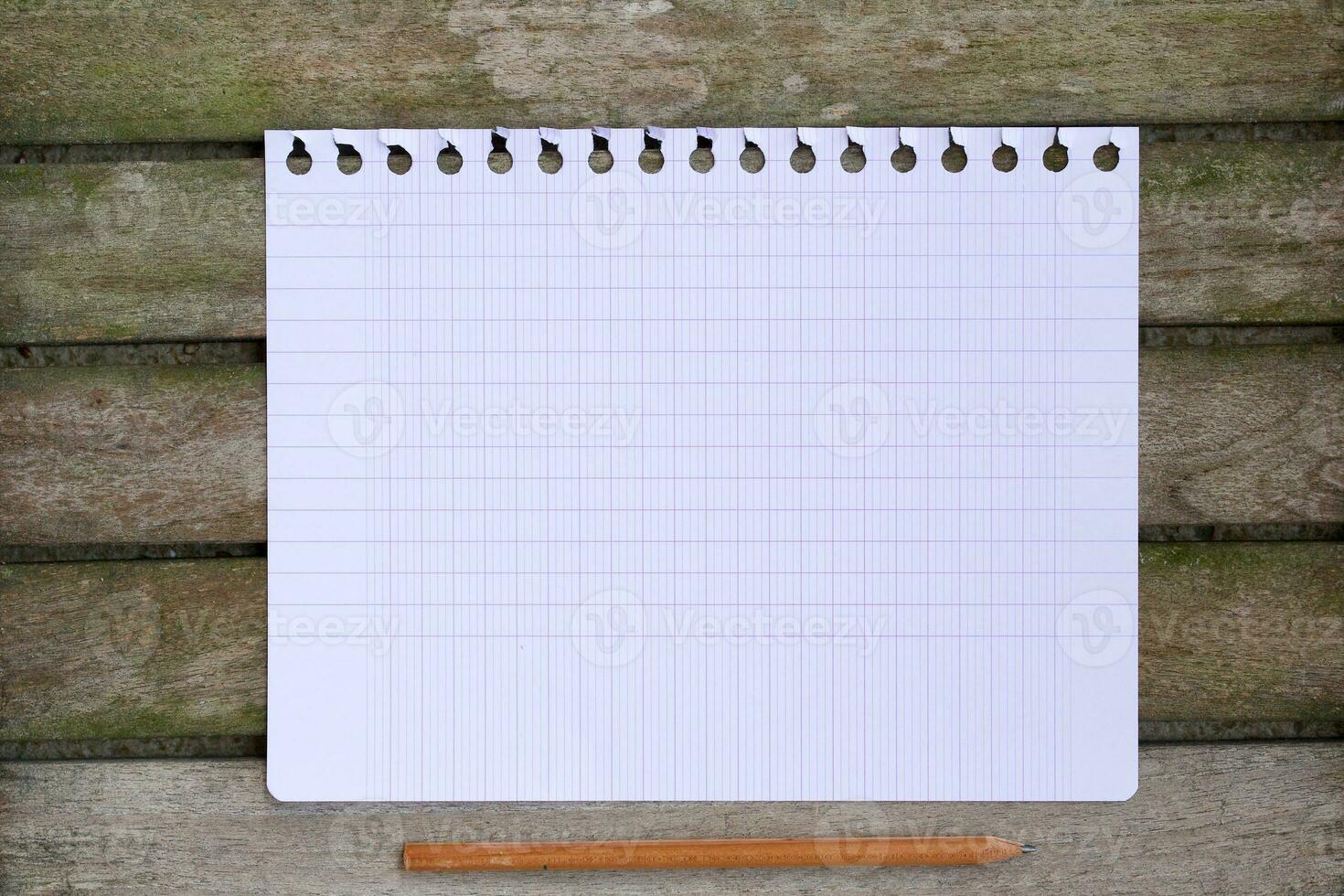 A sheet of paper on a wooden surface. Top view photo
