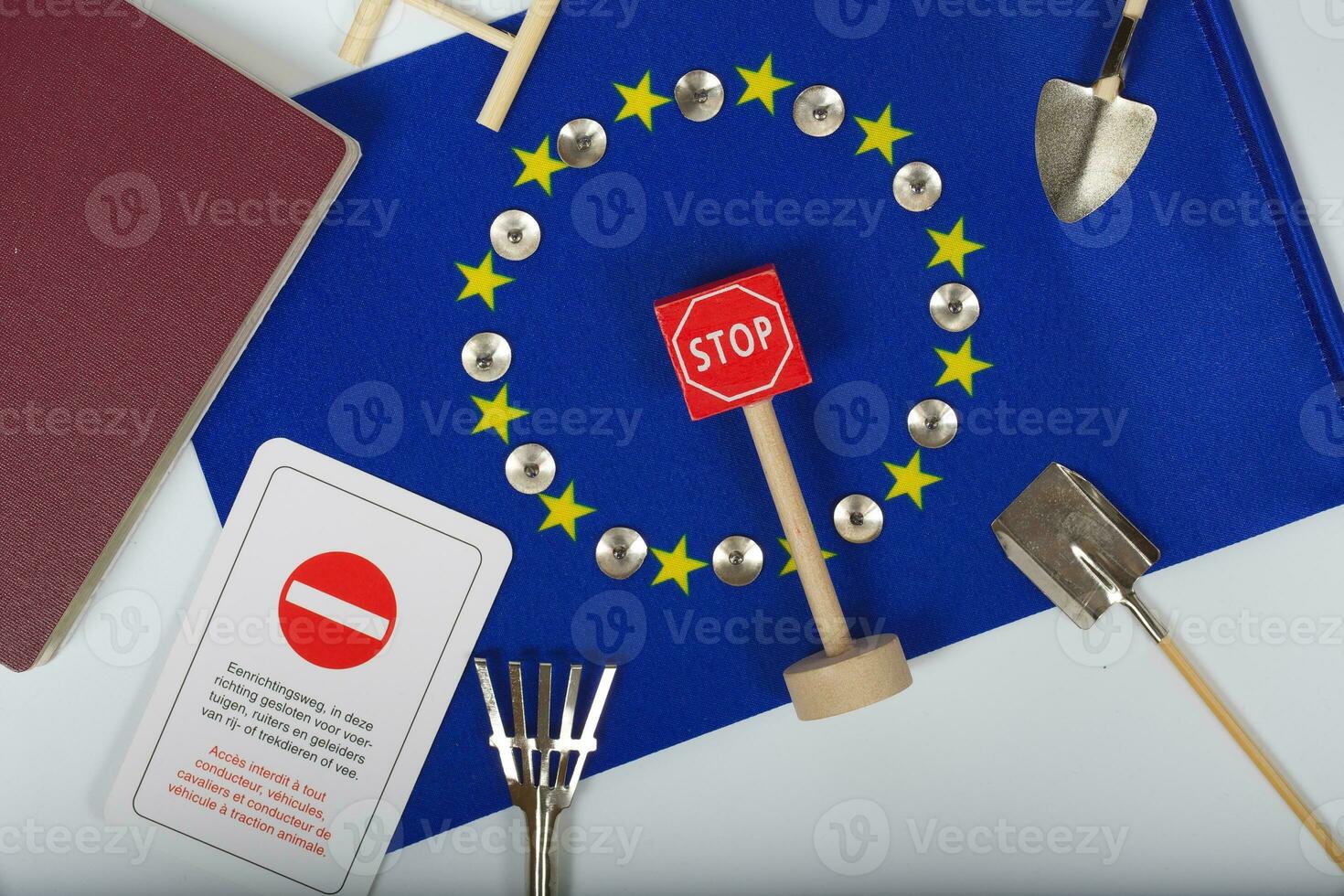 Agricultural tools,a card with access forbidden,pins,and a passport on an European flag.Closeup photo