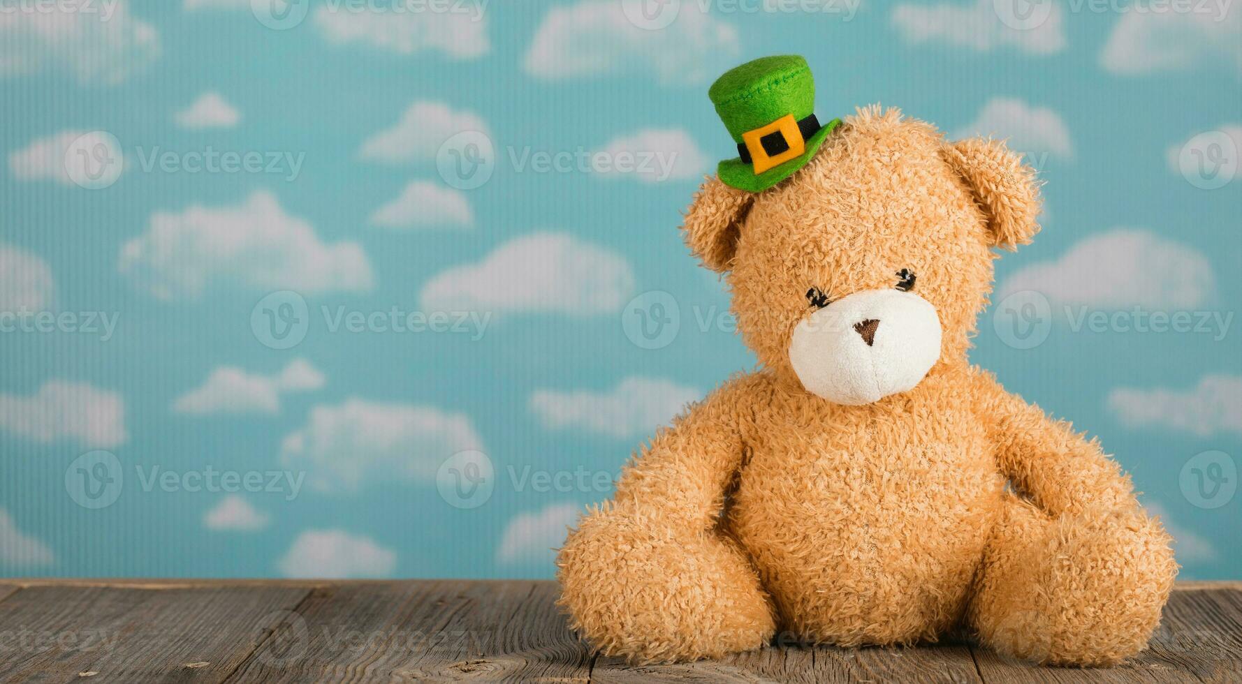 Brown plush teddy bear in a leprechaun hat on a wooden surface. photo