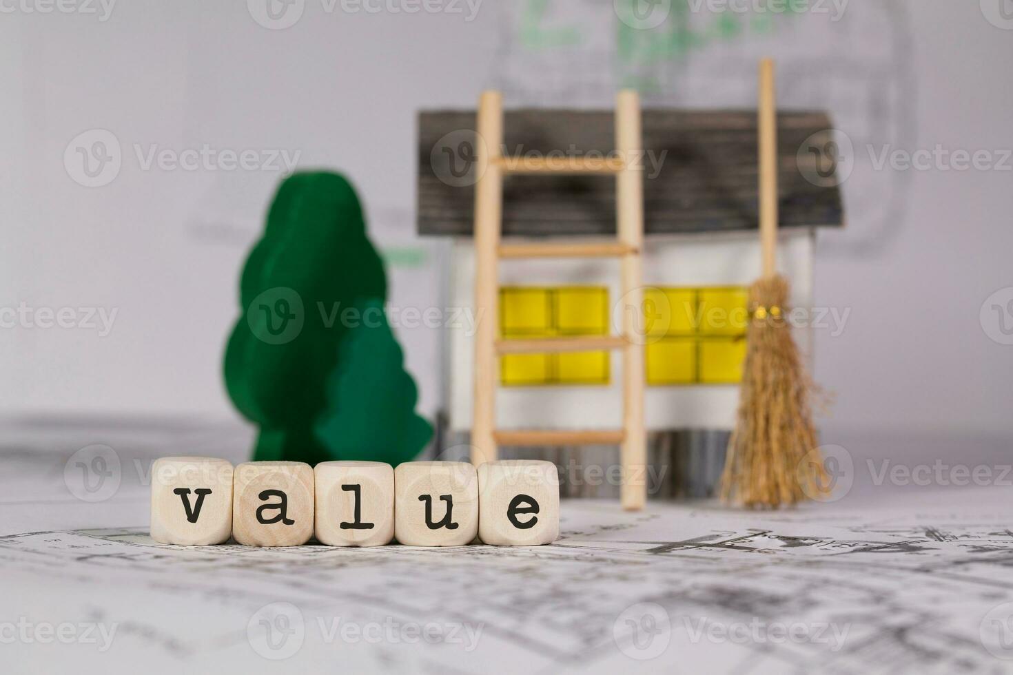 Word VALUE  composed of wooden letter. Small paper house, wooden trees in the background. photo