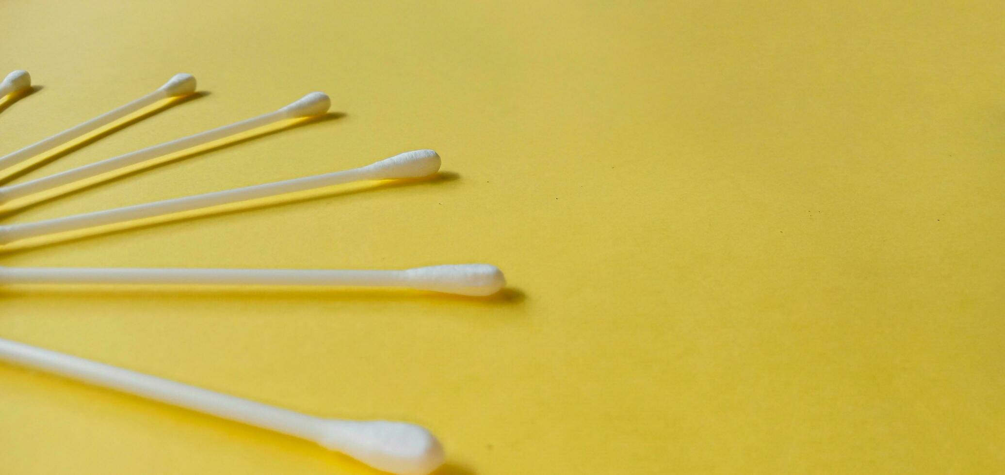 Heap of cotton swabs, cotton buds or cotton stick  on yellow background. Hygienic cosmetic and healthcare accessory. photo